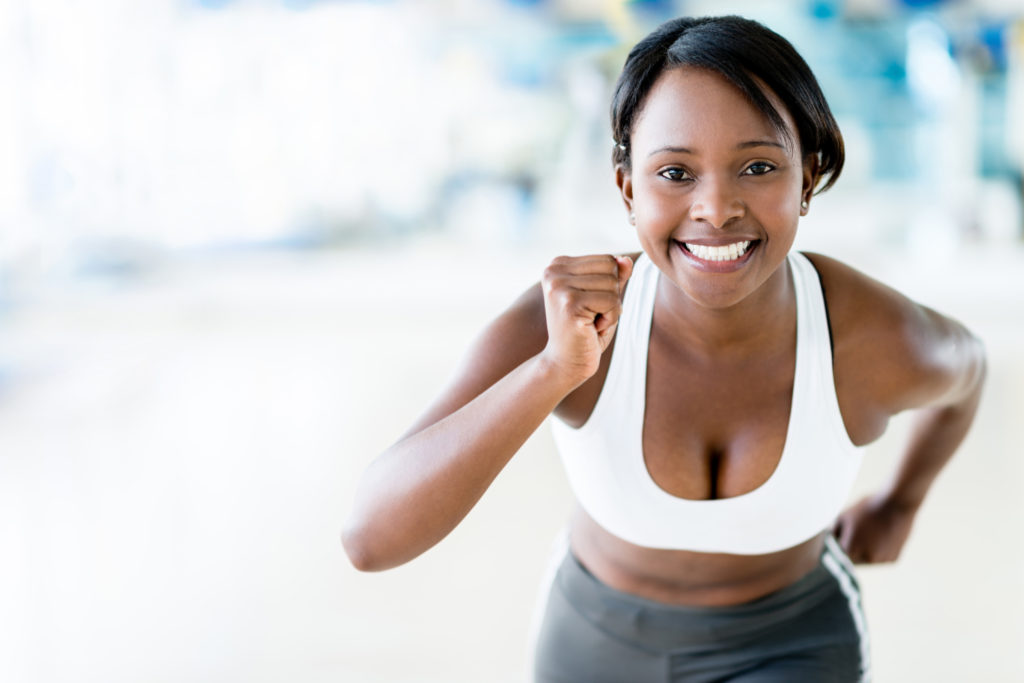 Competitive woman running at the gym looking happy